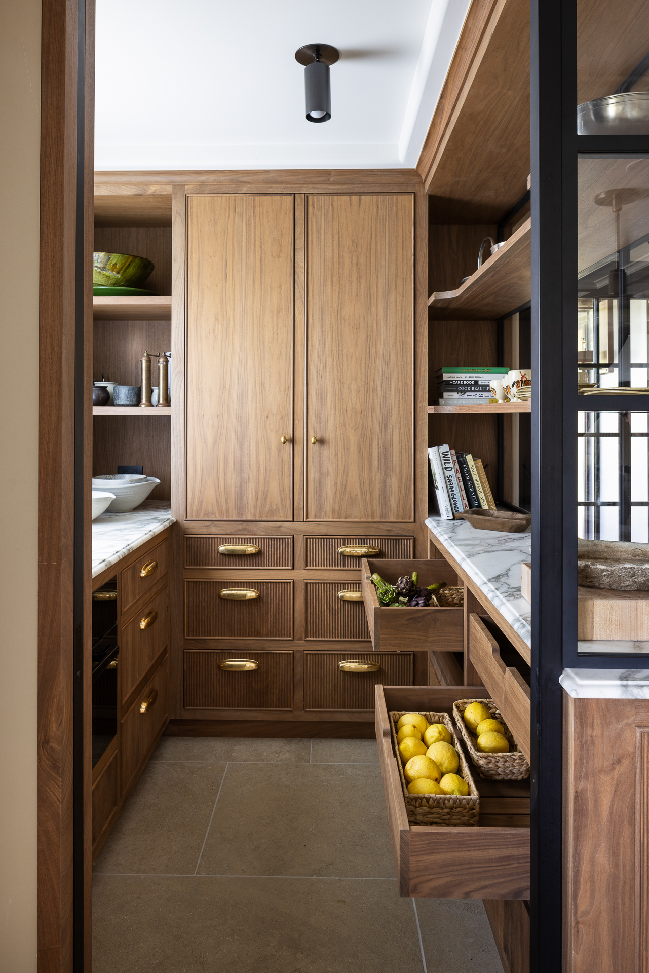 Walnut baking pantry with marble counters, open shelving and pull-out produce drawers
