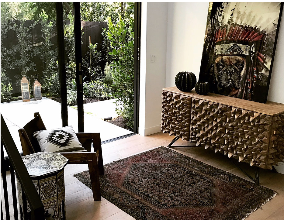 Interior with a carved console, artwork and a patterned rug
