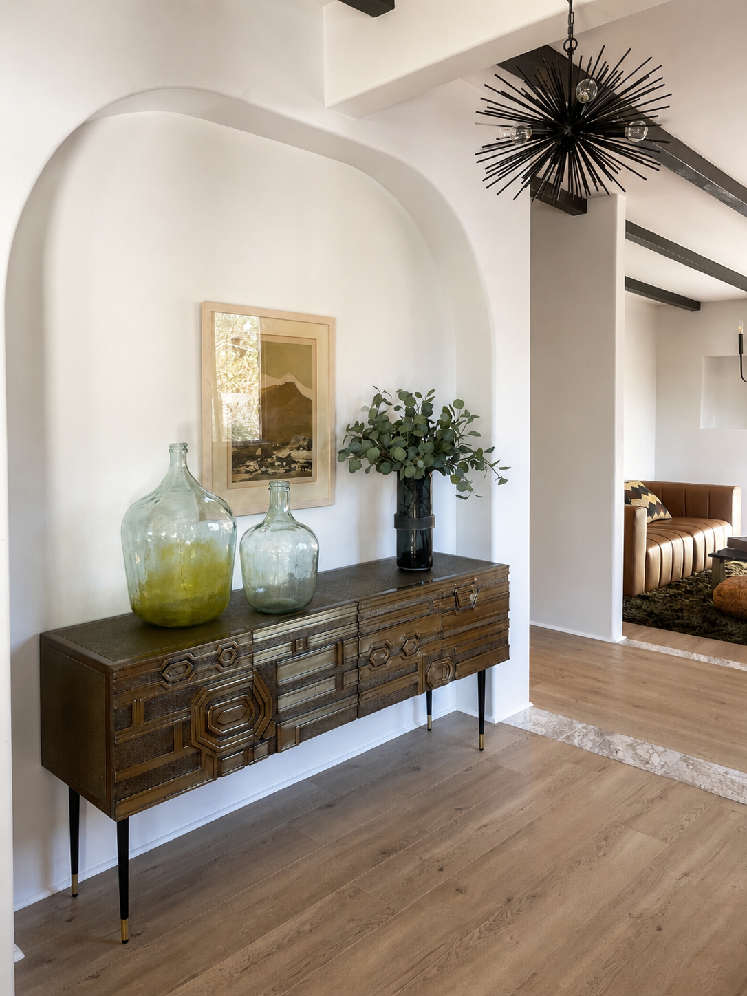 Vintage console and glass vessels beneath a curved niche at San Carlos